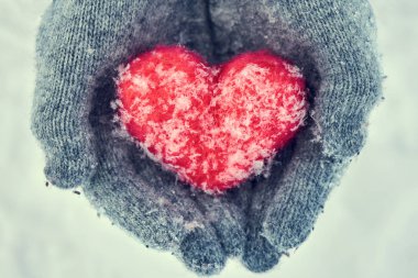 Erkek tutarak ve sakin bir kırmızı yün kalp açık havada kar taneleri ile korunmaya giyen yün eldiven eller. Sevgiler, healtcare. koruma, Sevgililer günü kavramı. Tonlu görüntü
