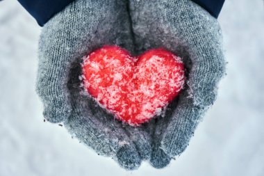 Holding ve sakin bir kırmızı yün kalbi koruyan yün eldiven eller açık havada kar taneleri ile kaplı. Sevgiler, healtcare. koruma, Sevgililer günü kavramı.