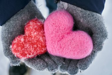 Yün eldiven donmuş kırmızı ve pembe yün kalpler holding eller açık havada kar taneleri ile kaplı. Sevgiler, healtcare. koruma, Sevgililer günü kavramı.