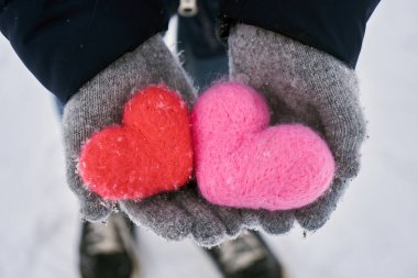 Yün eldiven donmuş kırmızı ve pembe yün kalpler tutan eller kar taneleri açık havada ile kaplı. Sevgiler, healtcare. koruma, Sevgililer günü kavramı.