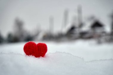 Kırmızı yün kalp üzerinde duran kabarık kar soğuk kışın arka planda Rus köy ile. Sevgililer günü, sağlık kavramı.