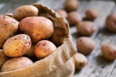 Çiğ patates bir çuvala kaba ahşap kurullarında yakın çekim