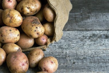 Ayakta zor ahşap kurullarında kadar bir çuvala ham unpeeled patates kapatın