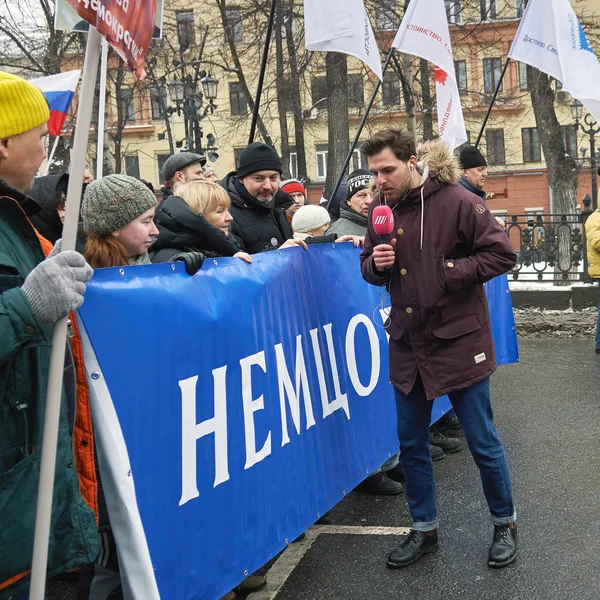 Репортер российского телеканала "Дождь" Алексей Коростелев берёт интервью у демонстрантов с политическим плакатом — стоковое фото