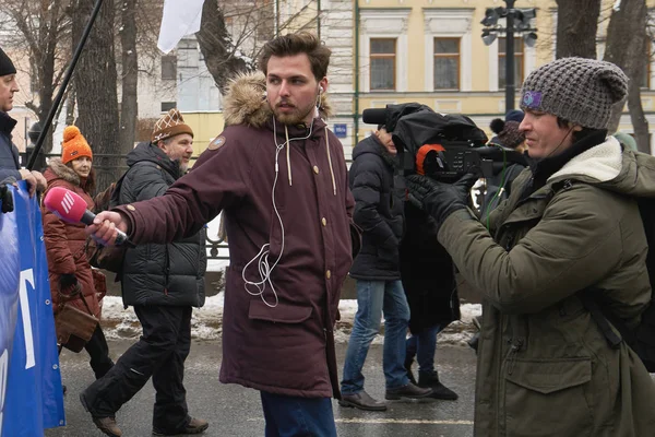 Репортер российского телеканала "Дождь" Алексей Коростелев берёт интервью у демонстрантов с политическим плакатом — стоковое фото