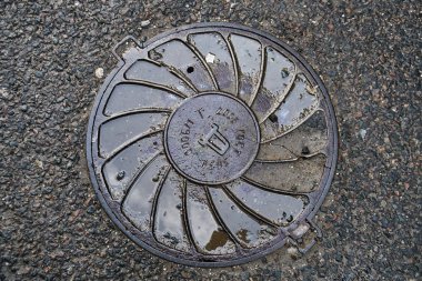 Eski Rus Sovyet kanalizasyon kapağı içinde asfalt