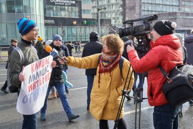 Moskova, Rusya - 10 Mart 2019. Siyasi bir afiş tutan genç bir gösterici görüşme kadın Tv muhabiri