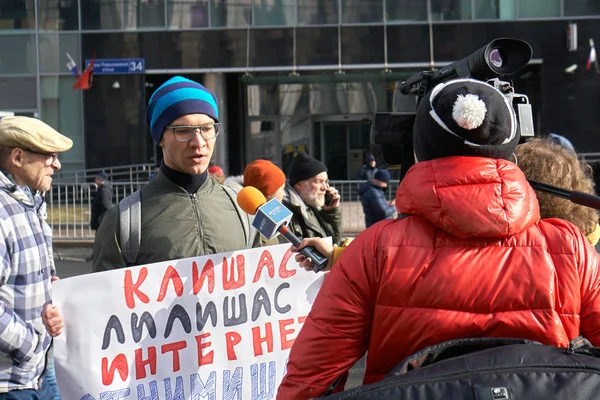 Москва, Россия - 10 марта 2019 года. Репортёр женского телевидения интервьюирует молодого демонстранта с политическим плакатом — стоковое фото