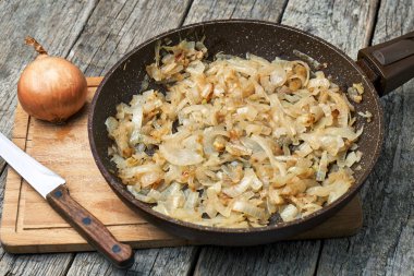 Taş kaplamalı ahşap masa üzerinde taze kızarmış soğan ile kızartma tavası