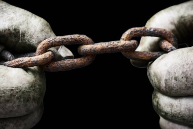 Güçlü erkek elleri siyah izole edilmiş eski paslı bir zinciri yırtmaya çalışıyor. Siyah beyaz fotoğraf.