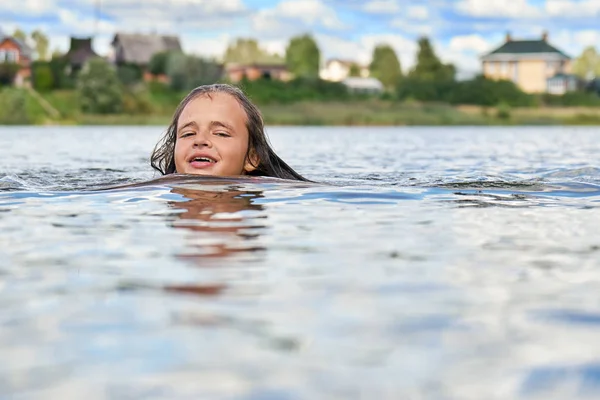 Une adolescente souriante nage dans un lac de banlieue russe en été — Photo