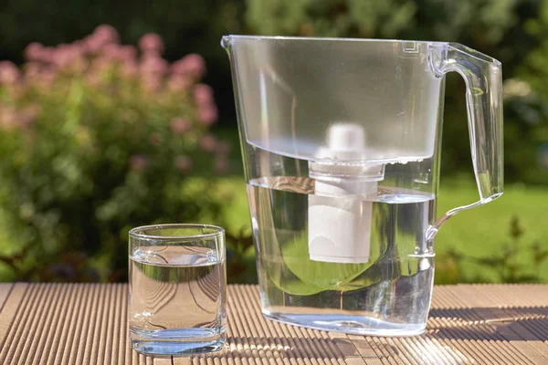 Water filter werper en een schoon glas van een helder water close-up op de zomertuin achtergrond — Stockfoto