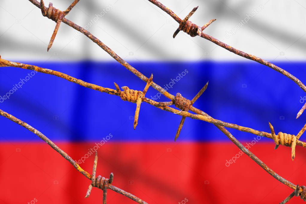 Russian flag behind rusty barbed wires with shadows