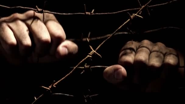 刑務所ランプのハードライトによって照らされた夜の暗闇の中でさびた有刺鉄線を振る汚い男性の手 Unfreedom コンセプト 解像度のビデオ — ストック動画