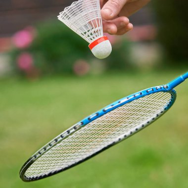 Kadın el beyaz bir badminton shuttlecock ve raket açık havada tutar