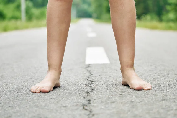 一个年轻女孩的赤脚站在柏油路上特写. — 图库照片