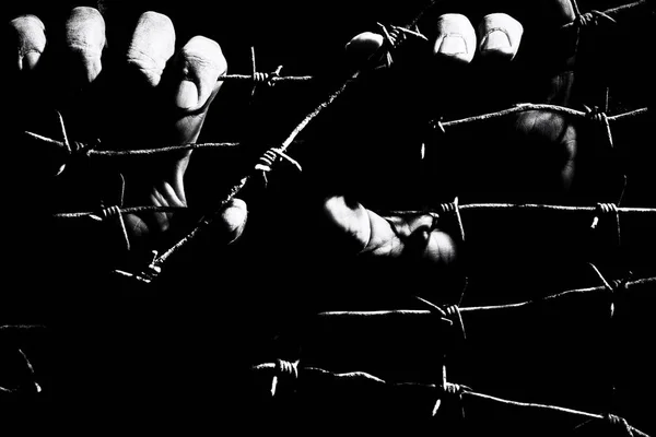 Mężczyzna ręce trzymać rozciągnięty zardzewiałe drut kolczowy w ciemności — Zdjęcie stockowe