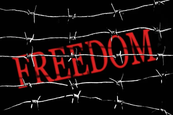 Das Wort Freiheit schrieb mit roter Farbe hinter weißen Silhouetten aus Stacheldrähten — Stockfoto