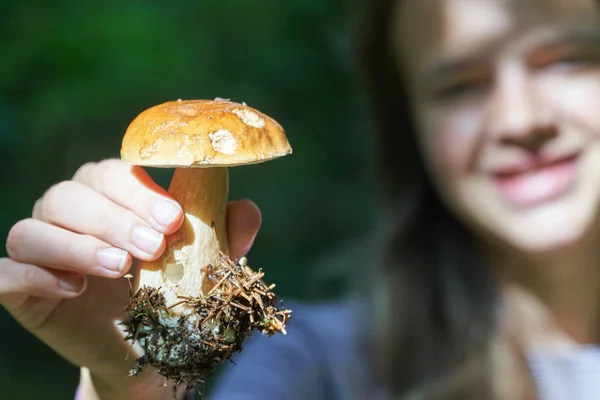 Adolescente muestra una seta boletus edulis en la mano en el bosque —  Fotos de Stock