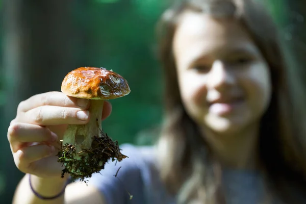 Adolescente chica mostrando un hongo boletus edulis en la mano en el bosque —  Fotos de Stock