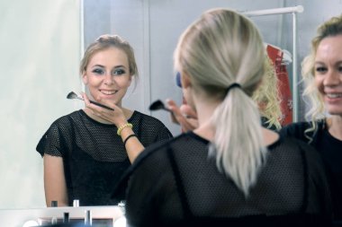 Makyaj sanatçısı ayna önünde genç bir model için makyaj yapma