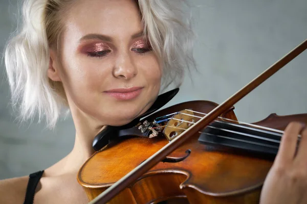 Young blonde beautiful woman violinist plays violin close up