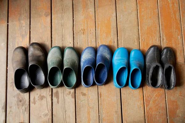 Cinco pares de viejas botas de goma de la familia en el piso de madera —  Fotos de Stock