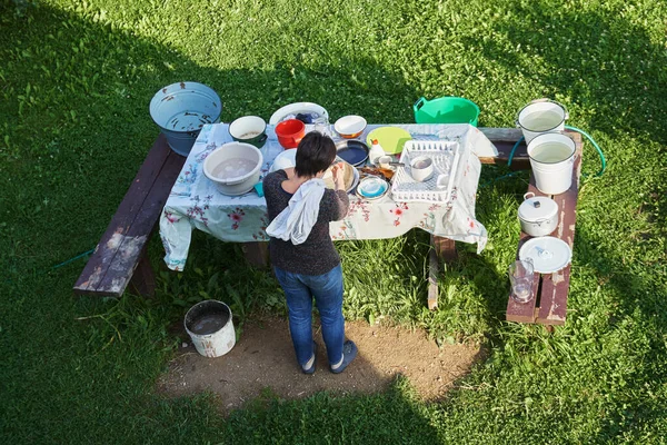 Frau spült im Sommer dreckiges Geschirr im Freien ab — Stockfoto