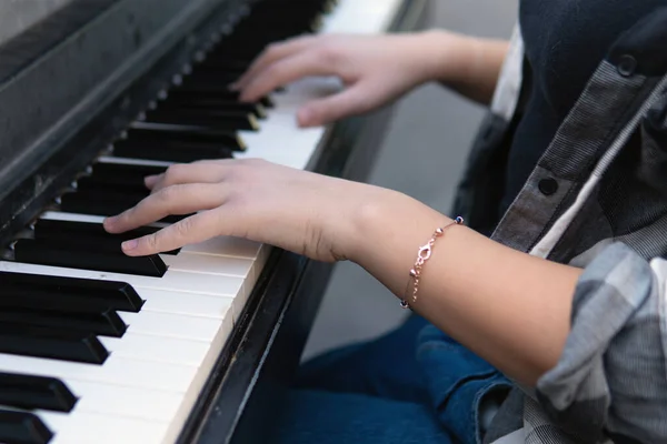 Закрыть руки девочки-подростка, играющей на фортепиано на открытом воздухе — стоковое фото
