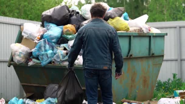 身着斜纹棉布西服的男子把一个装满塑料的垃圾袋扔进户外垃圾箱 — 图库视频影像