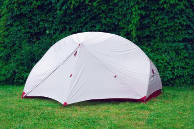 Turist çadırı yaz aylarında yapraklı arka planda kısa yeşil çimlere kurulur.