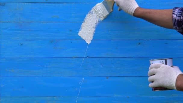 Pintor dibuja un signo de interrogación con pintura blanca en una pared azul con un pincel — Vídeos de Stock