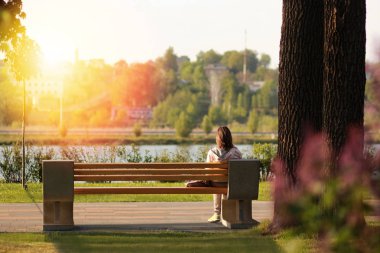 Sunset bulvarında göl yakınındaki parkta bir bankta oturan yalnız genç kadın
