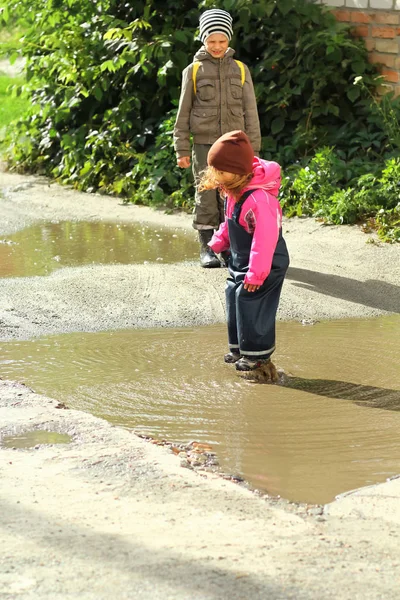Children jumping and splashing in muddy puddles
