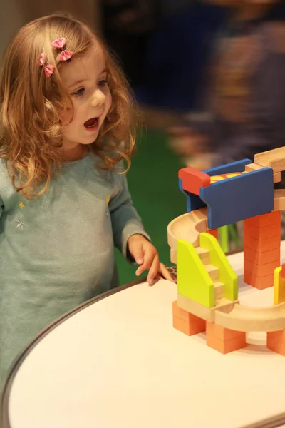 Emotional toddler girl excited of the basics of physics and mechanics demonstrated at the nursery