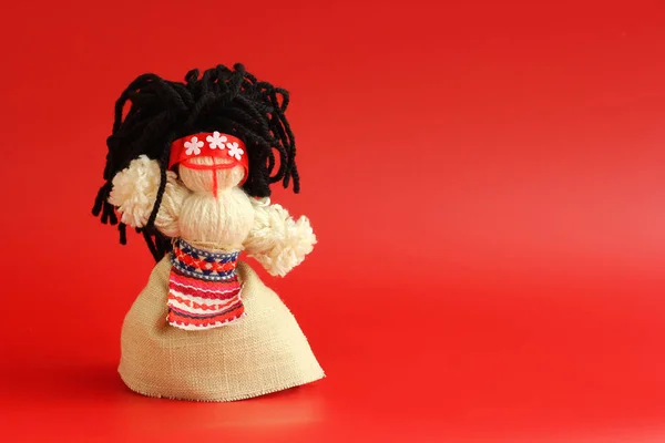 Handmade Motanka doll - traditional ukrainian doll, symbol of fertility and household guardian. Red background with negatice space
