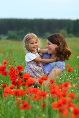 Çiçek açan Poppies alanında mutlu sarılma anne ve kızı yaz portresi