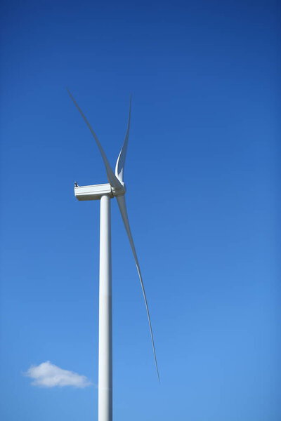 Profile view of wind power energy generator against blue sky
