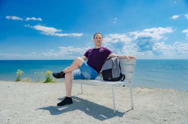 bir tezgah ve denize bakarak bir adam oturuyor.