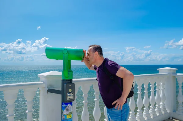 Un homme à l'âge, touriste regardant à travers le télescope . — Photo