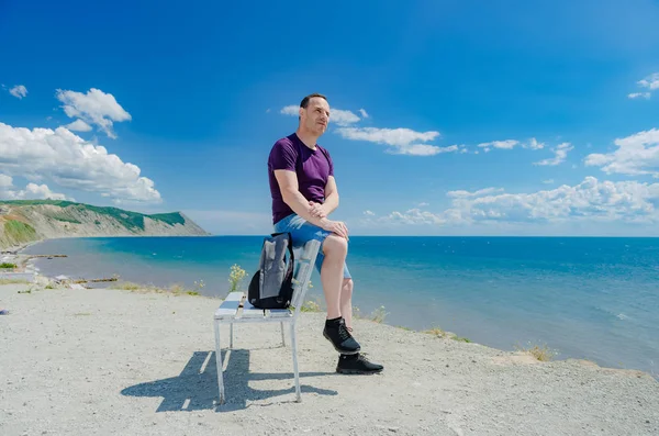 Un homme assis sur un banc et regardant la mer . — Photo