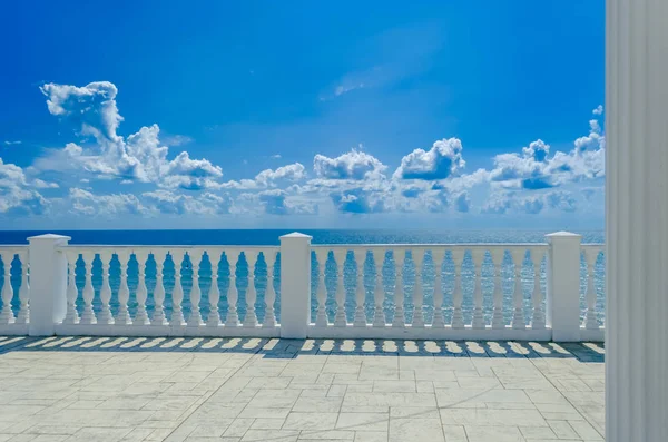 바다, 하늘, 하얀 구름의 멋진 전망을 감상할 수 있는 하얀 남바라기가 있는 테라스. 로열티 프리 스톡 이미지
