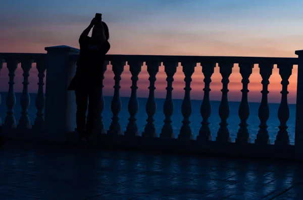 Fence of balusters against the sunset and the sea