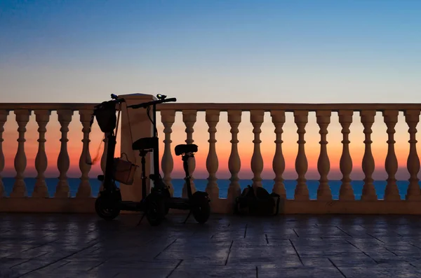 Two with a backpack and a women's bag tourists left near the fence with balusters against the sunset by the sea. — Stock Photo, Image