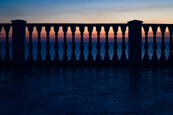 Geländer gegen Sonnenuntergang und Meer Stockbild