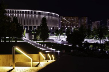 Stadyuma bakan fenerler ile aydınlatılmış parkta yürüyüş yolu. Krasnodar Parkı.