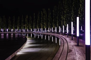 Krasnodar Parkı'ndaki çeşme boyunca fenerlerle simetrik olarak düzenlenmiş ağaçlar.