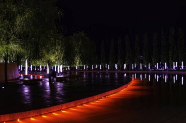 Krasnodar Parkı'ndaki çeşme boyunca fenerlerle simetrik olarak düzenlenmiş ağaçlar.