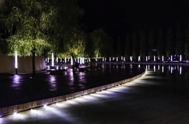 Krasnodar Parkı'ndaki çeşme boyunca fenerlerle simetrik olarak düzenlenmiş ağaçlar.