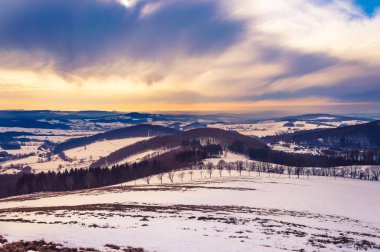 Majestic winter landscape with snow and dramatic sky in Rhoen Mountains, Germany clipart